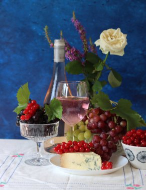 Grapes, wine and cheese on a table. Colorful summer still life on textured background with copy space.