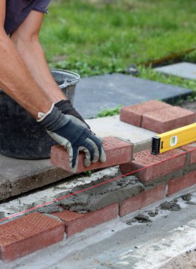 Close up photo of male hands holding red brick. Construction site concept. Professional build brick wall. 