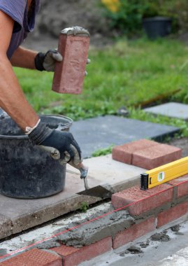 Construction work in progress. Male builder working with red bricks. Masonry wall close up photo.  