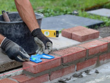 Close up photo of male hands holding red brick. Construction site concept. Professional build brick wall. 