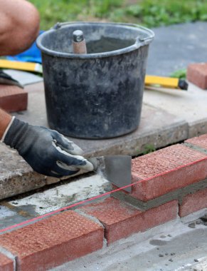 Construction work in progress. Male builder working with red bricks. Masonry wall close up photo.  