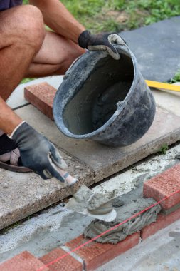 Close up photo of male hands holding red brick. Construction site concept. Professional build brick wall. 