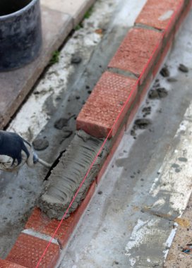 Construction work in progress. Male builder working with red bricks. Masonry wall close up photo.  