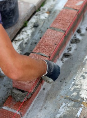 Close up photo of male hands holding red brick. Construction site concept. Professional build brick wall. 