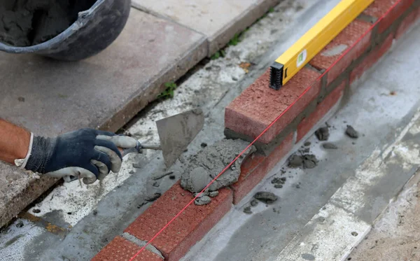 Construction work in progress. Male builder working with red bricks. Masonry wall close up photo.  