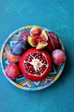 Mavi seramik tabakta taze Akdeniz meyvesi. Nar, incir ve erikle dolu renkli bir hayat. Sağlıklı yeme kavramı. 
