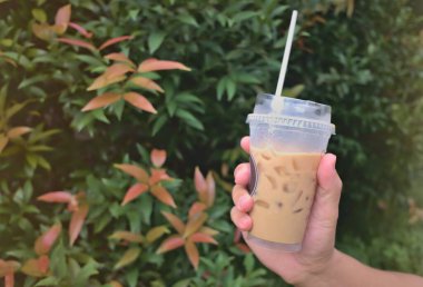 coffee cup in hand red flower tree background.copyscape