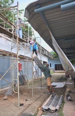 Construction workers deliver roof tiles Renovated old building Three workers Construction scaffolding Asian workers
