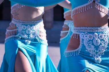 Üç orta yaşlı İspanyol kadının göbek dansı için turkuaz kostümler ve yapay elmaslar giymesi. Göbek dansı konsepti.