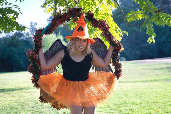 오렌지 모자와 치마를 날개를 나무에 매달려 여성의 할로윈 구부정 — 스톡 사진
