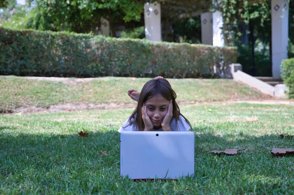 Mädchen Liegt Gras Einem Park Und Schaut Auf Ein Tablet — Stockfoto