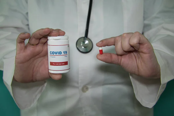 医生手的细部 用白色外套和听诊器 一只手拿着一瓶抗Covid 19病毒的抗病毒药丸 另一只手拿着一颗药丸 流行病概念 — 图库照片