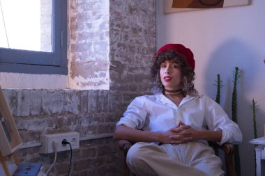 Genç kadın, sanatçı, tasarımcı ve kırmızı bereli ressam portresi stüdyosunda elleri bağlı oturuyor. Konsept resim, çizim, sanatçı, tasarımcı, modern.