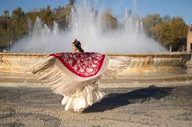 Genç flamenko kadın, İspanyol ve esmer, tipik flamenko dans takımı ile, altın çiçeklerle kırmızı manila şalla dans ediyor. Flamenko konsepti, dansçı, tipik İspanyol dansı..