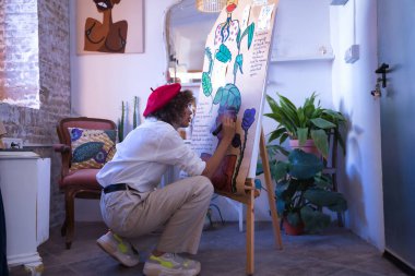 Genç bir kadın, sanatçı, tasarımcı ve ressam atölyesinde siyah bir kalemle eserlerinden biri üzerinde çalışıyor. Konsept resim, çizim, tasarımcı, sanatçı, modern.