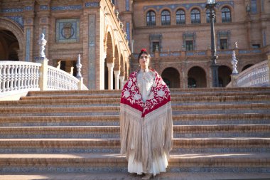 Genç flamenko kadın, İspanyol ve esmer, tipik flamenko dans takımı, kırmızı manila şal ve altın çiçekler, merdivenlerde poz. Flamenko konsepti, dansçı, tipik İspanyol dansı..