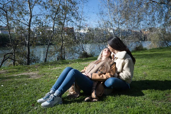 Skutečná Dvojice Mladých Žen Sedících Trávníku Parku Objímajících Láskyplně Hledících — Stock fotografie