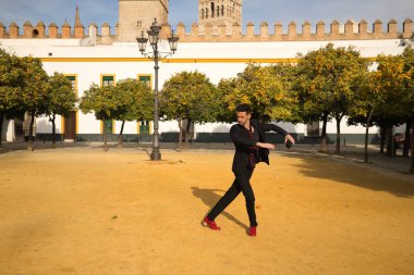 Siyah gömlek, ceket ve pantolon giyen, kırmızı dans ayakkabısı giyen ve kırmızı noktalı siyah mendili olan genç bir İspanyol. Sokakta flamenko dansı yapıyor. Sanat, dans, kültür kavramı.