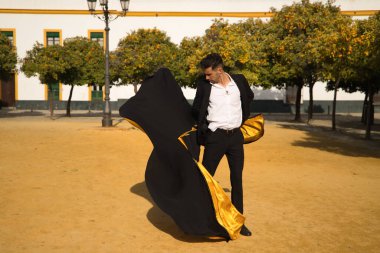 Siyah gömlekli, ceketli ve pantolonlu, dans ayakkabılı, siyah ve altın pelerinli, flamenko dansı yapan genç bir İspanyol. Tipik İspanyol konsepti, sanat, dans, kültür, gelenek.