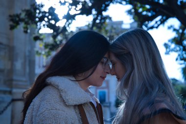 Gerçek bir çift genç kadın, sevgi dolu bir tavırla gözlerini kapatarak alınlarını birleştiriyor. Kavram lgtbiq +, lezbiyenler, aşık, dahil olma.