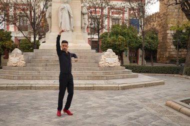 Siyah gömlek ve pantolon giyen, kırmızı dans ayakkabılı, sokakta flamenko dansı yapan genç bir İspanyol. Tipik İspanyol konsepti, sanat, dans, kültür, gelenek.