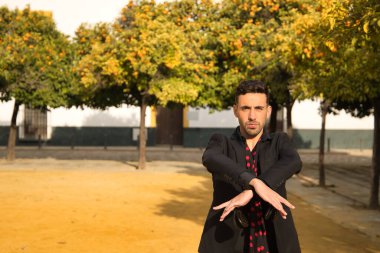 Siyah gömlek ve ceket giyen, kırmızı noktalı siyah mendilli ve kastanyetli genç İspanyol 'un portresi sokakta flamenko dansı yapıyor. Sanat, dans, kültür, gelenek.