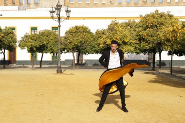 Siyah gömlekli, ceketli ve pantolonlu, dans ayakkabılı, siyah ve altın pelerinli, flamenko dansı yapan genç bir İspanyol. Tipik İspanyol konsepti, sanat, dans, kültür, gelenek.