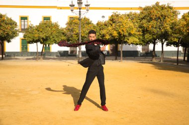 Siyah tişörtlü, ceketli ve pantolonlu, kırmızı dans ayakkabılı, siyah mendilli, kırmızı benekli genç bir İspanyol. Sanat, dans, kültür, gelenek.