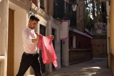 Beyaz gömlekli ve siyah pantolonlu genç bir İspanyol 'un portresi sokakta beyaz benekli kırmızı bir mendille flamenko dansı yapıyor. Tipik İspanyol konsepti sanat, dans, kültür, gelenek.
