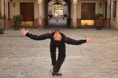 Sakallı, at kuyruklu, siyah şeffaf gömlekli, siyah puantiyeli, kırmızı güllü, siyah pantolonlu ve ceketli, şehirde flamenko dansı yapan genç bir adam. Sanat, dans, kültür, gelenek.