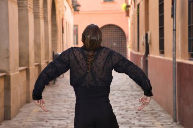 Sakallı, at kuyruklu, siyah şeffaf gömlekli, siyah benekli, siyah pantolonlu ve ceketli, şehirde flamenko dansı yapan genç bir adam. Sanat, dans, kültür, gelenek.