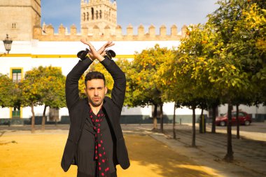 Siyah gömlek ve ceket giyen, kırmızı noktalı siyah mendilli ve kastanyetli genç İspanyol 'un portresi sokakta flamenko dansı yapıyor. Sanat, dans, kültür, gelenek.