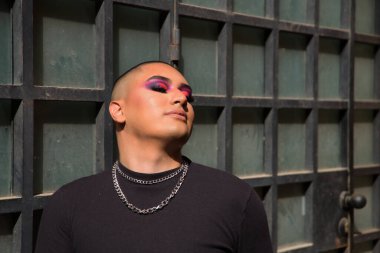 İkili olmayan bir kişinin portresi, genç ve Güney Amerikalı, gözleri kapalı, güneş ışınlarını alıyor. Kavram kraliçesi, lgbtq +, gurur, nonoş.