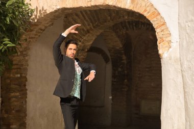 Ceketli, pantolonlu, siyah dans ayakkabılı, beyaz gömlekli, yeşil yelekli, sokakta flamenko dansı yapan genç bir İspanyol. Tipik İspanyol konsepti, sanat, dans, kültür, gelenek.