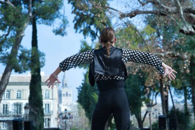 Sakallı, at kuyruklu, siyah tişörtlü, beyaz benekli, siyah pantolonlu ve ceketli, sahnede flamenko dansı yapan genç bir adam. Sanat, dans, kültür, gelenek.