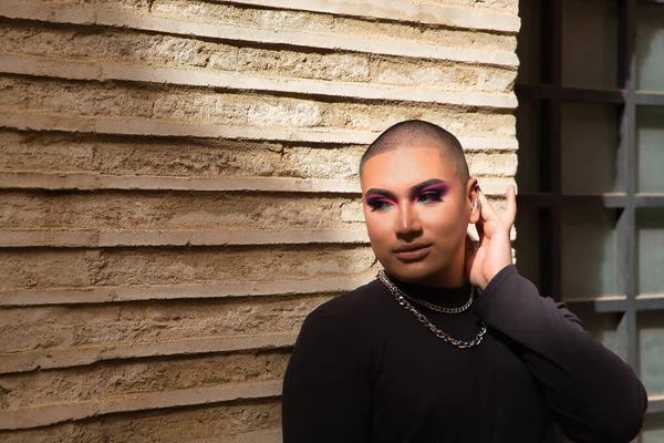 İkili olmayan birinin portresi, genç ve Güney Amerikalı, ağır ağır tuğla bir duvarda, güneş ışınları alıyor. Kavram kraliçesi, lgbtq +, gurur, nonoş.