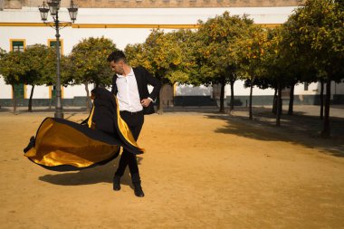 Siyah gömlekli, ceketli ve pantolonlu, dans ayakkabılı, siyah ve altın pelerinli, flamenko dansı yapan genç bir İspanyol. Tipik İspanyol konsepti, sanat, dans, kültür, gelenek.