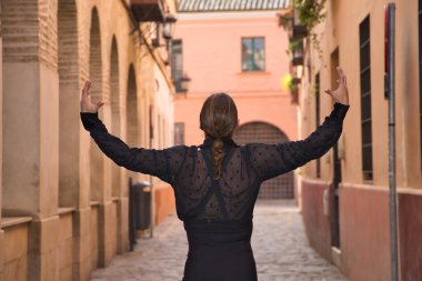 Sakallı, at kuyruklu, siyah şeffaf gömlekli, siyah benekli, siyah pantolonlu ve ceketli, şehirde flamenko dansı yapan genç bir adam. Sanat, dans, kültür, gelenek.