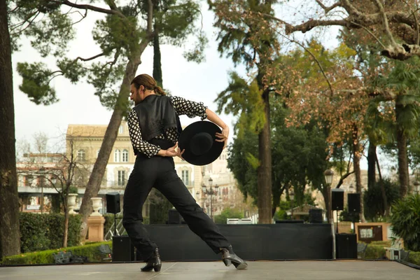 Sakallı, at kuyruklu, siyah tişörtlü, beyaz benekli, siyah pantolonlu ve ceketli, sahnede şapkalı flamenko dansı yapan genç bir adam. Sanat, dans, kültür, gelenek.