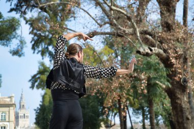 Sakallı, at kuyruklu, siyah tişörtlü, beyaz benekli, siyah pantolonlu ve ceketli, sahnede flamenko dansı yapan genç bir adam. Sanat, dans, kültür, gelenek.