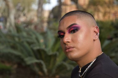 İkili olmayan birinin portresi, genç ve Güney Amerikalı, ağır makyajlı, yüzünde parlak taşlar var. Kavram kraliçesi, lgbtq +, gurur, nonoş.