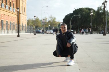 İkili olmayan, genç ve Güney Amerikalı, aşırı makyajlı, tamamen siyah giyinmiş, Avrupa 'da tatilde çömelmiş poz veriyor. Kavram kraliçesi, lgbtq +, gurur, nonoş.