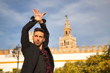 Siyah gömlek ve ceket giyen, kırmızı noktalı siyah mendilli ve kastanyetli genç İspanyol 'un portresi sokakta flamenko dansı yapıyor. Sanat, dans, kültür, gelenek.