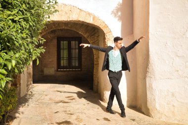 Ceketli, pantolonlu, siyah dans ayakkabılı, beyaz gömlekli, yeşil yelekli, sokakta flamenko dansı yapan genç bir İspanyol. Tipik İspanyol konsepti, sanat, dans, kültür, gelenek.