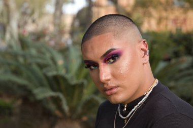 İkili olmayan birinin portresi, genç ve Güney Amerikalı, ağır makyajlı, yüzünde parlak taşlar var. Kavram kraliçesi, lgbtq +, gurur, nonoş.