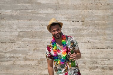 Genç ve yakışıklı bir adam, mavi gözlü, mükemmel gülüşlü, sakallı, şapkalı, Hawaii gömlekli ve elinde gri bir arka planda bira şişesi olan çiçek kolyeli. Tatiller, partiler, geziler, içkiler.