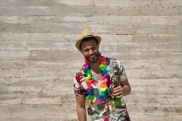 Genç ve yakışıklı bir adam, mavi gözlü, mükemmel gülüşlü, sakallı, şapkalı, Hawaii gömlekli ve elinde gri bir arka planda bira şişesi olan çiçek kolyeli. Tatiller, partiler, geziler, içkiler.