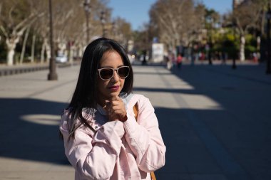 Pembe ceketli, güneş gözlüklü, elleri bağlı dua eden güzel bir Güney Amerikalı kadın. Dini, duayı, katoliği, inancı kavra.