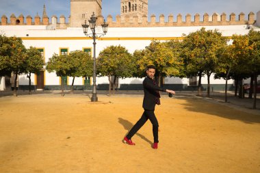 Siyah gömlek, ceket ve pantolon giyen, kırmızı dans ayakkabısı giyen ve kırmızı noktalı siyah mendili olan genç bir İspanyol. Sokakta flamenko dansı yapıyor. Sanat, dans, kültür kavramı.