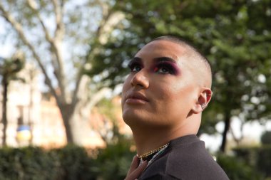 İkili olmayan birinin portresi, genç ve Güney Amerikalı, ağır makyajlı, yüzünde parlak taşlar var. Kavram kraliçesi, lgbtq +, gurur, nonoş.